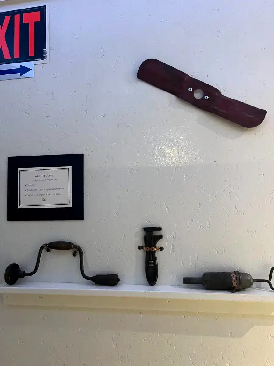 Antique grease gun, wood auger and wrench on hallway shelf